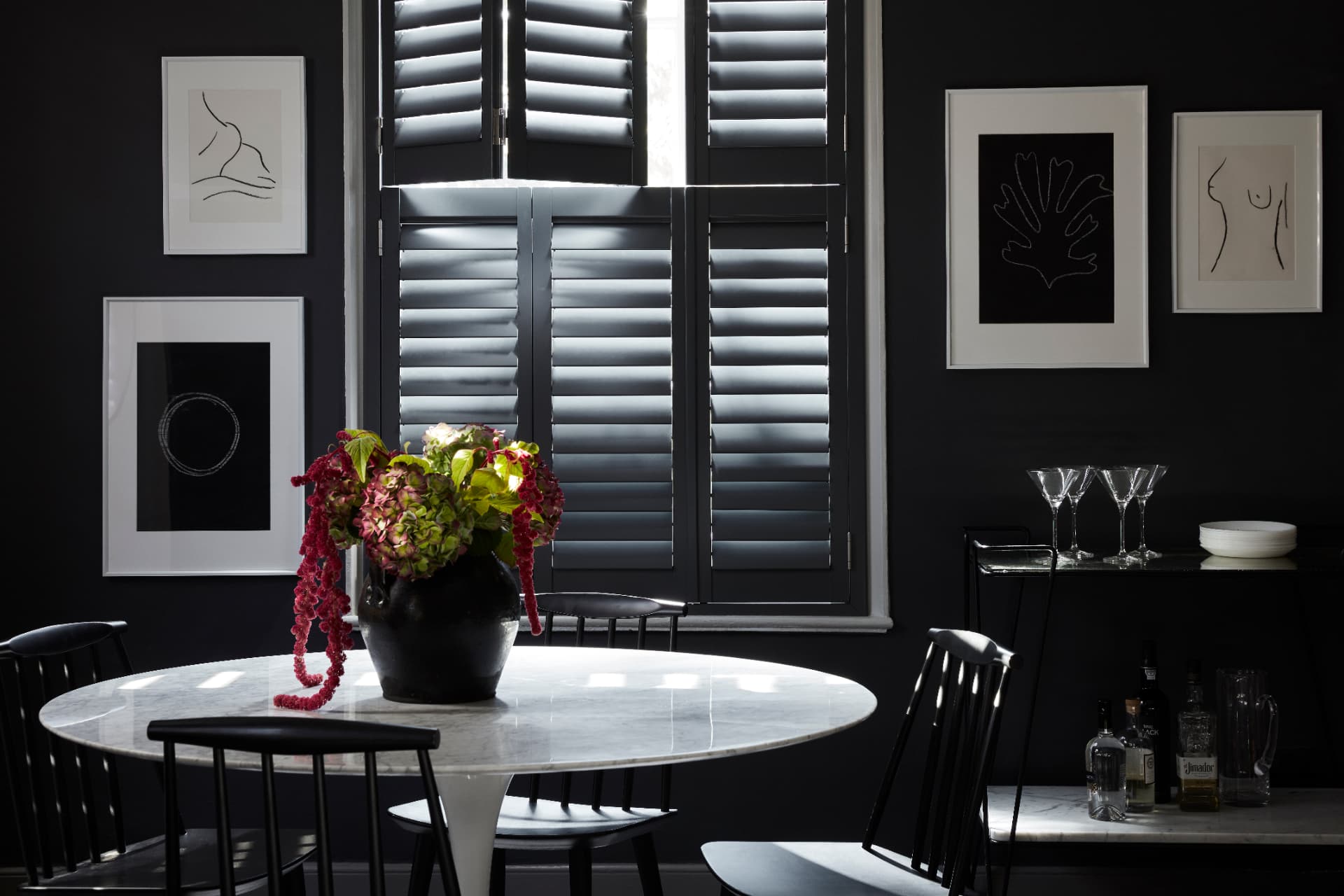 Charcoal tier-on-tier shutters in a dark painted dining room