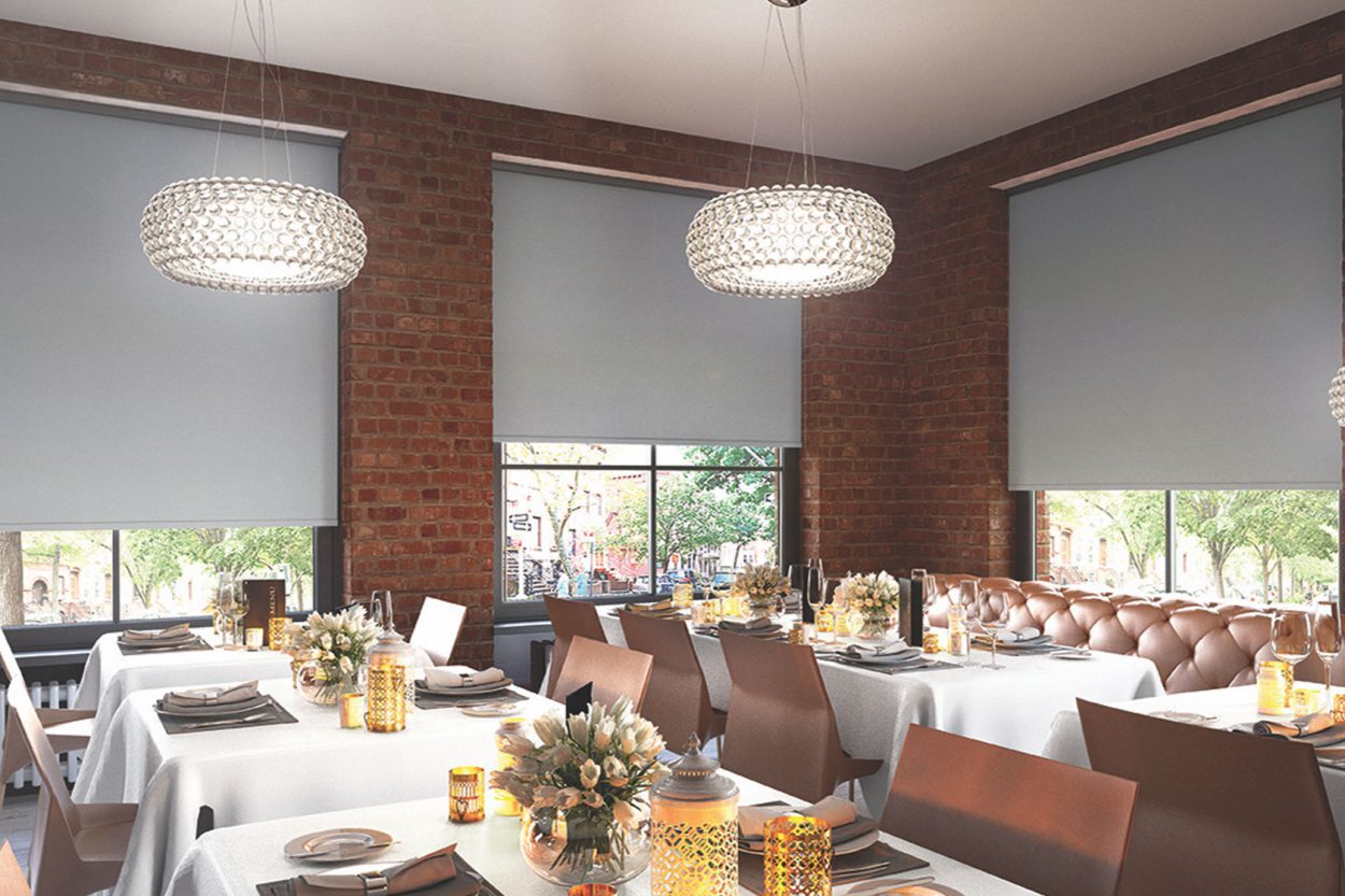 Roller blinds in a restaurant dining room with exposed brick