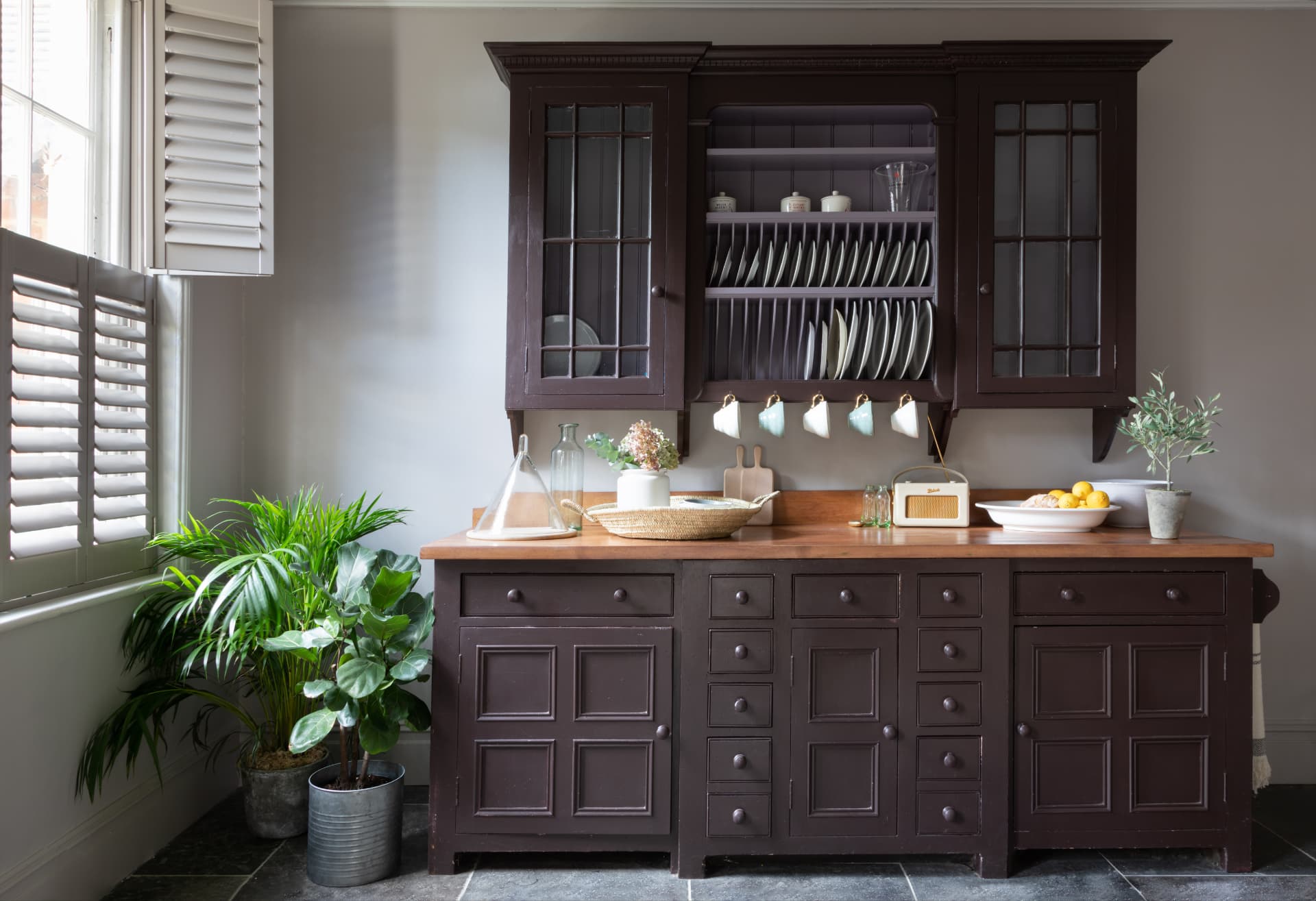 Off-white tier-on-tier shutters beside a painted kitchen dresser