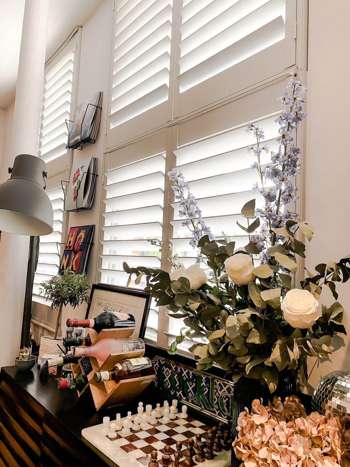White full height shutters in a book-lined living room