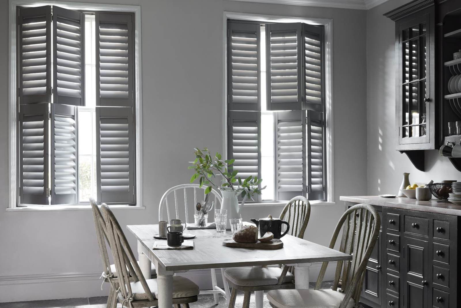 Grey tier-on-tier shutters with 76mm louvres in a kitchen dining room