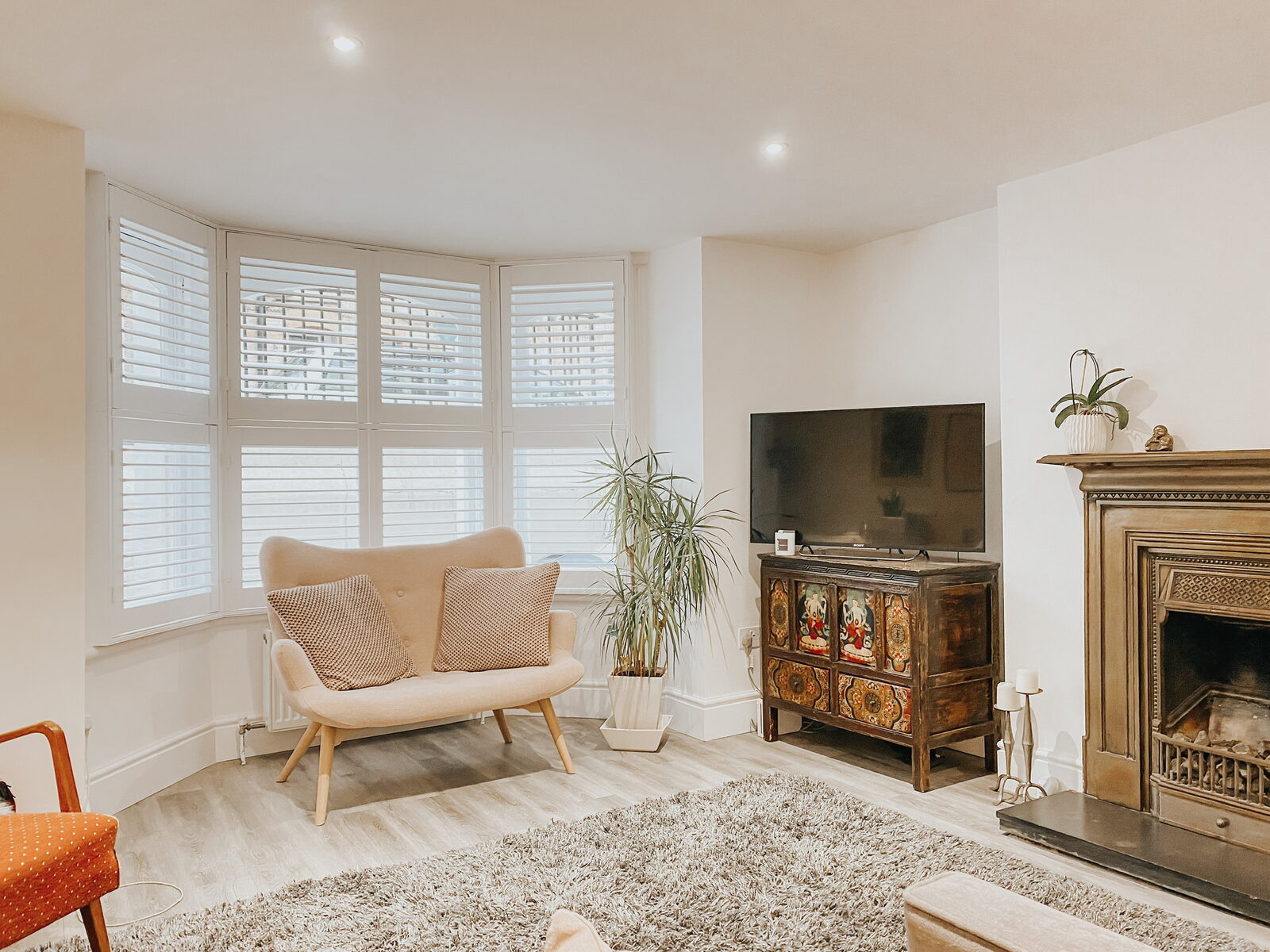 White shutters in a living room beside a period fireplace