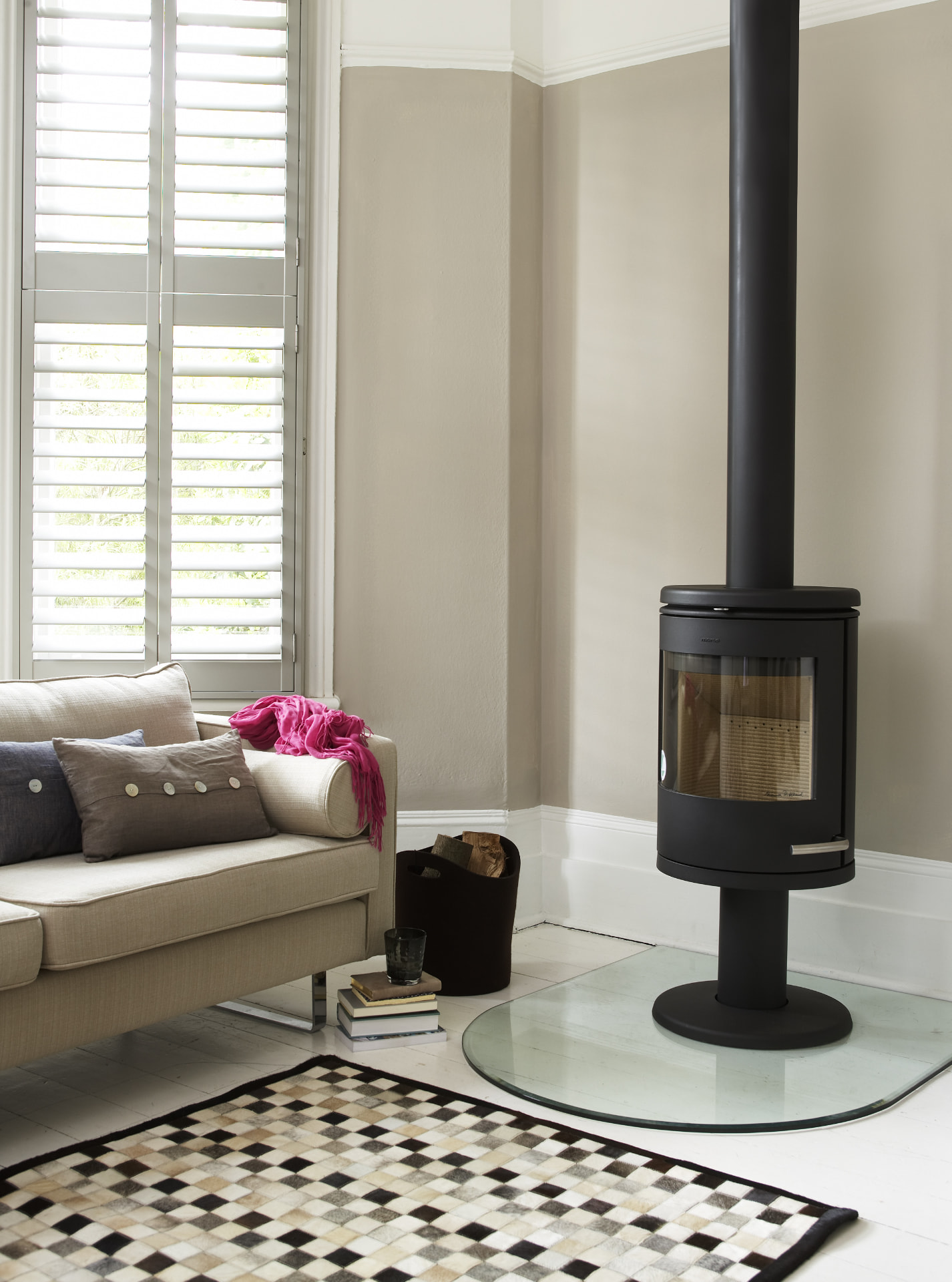 Tier-on-tier shutters beside a wood burning stove in a neutral lounge