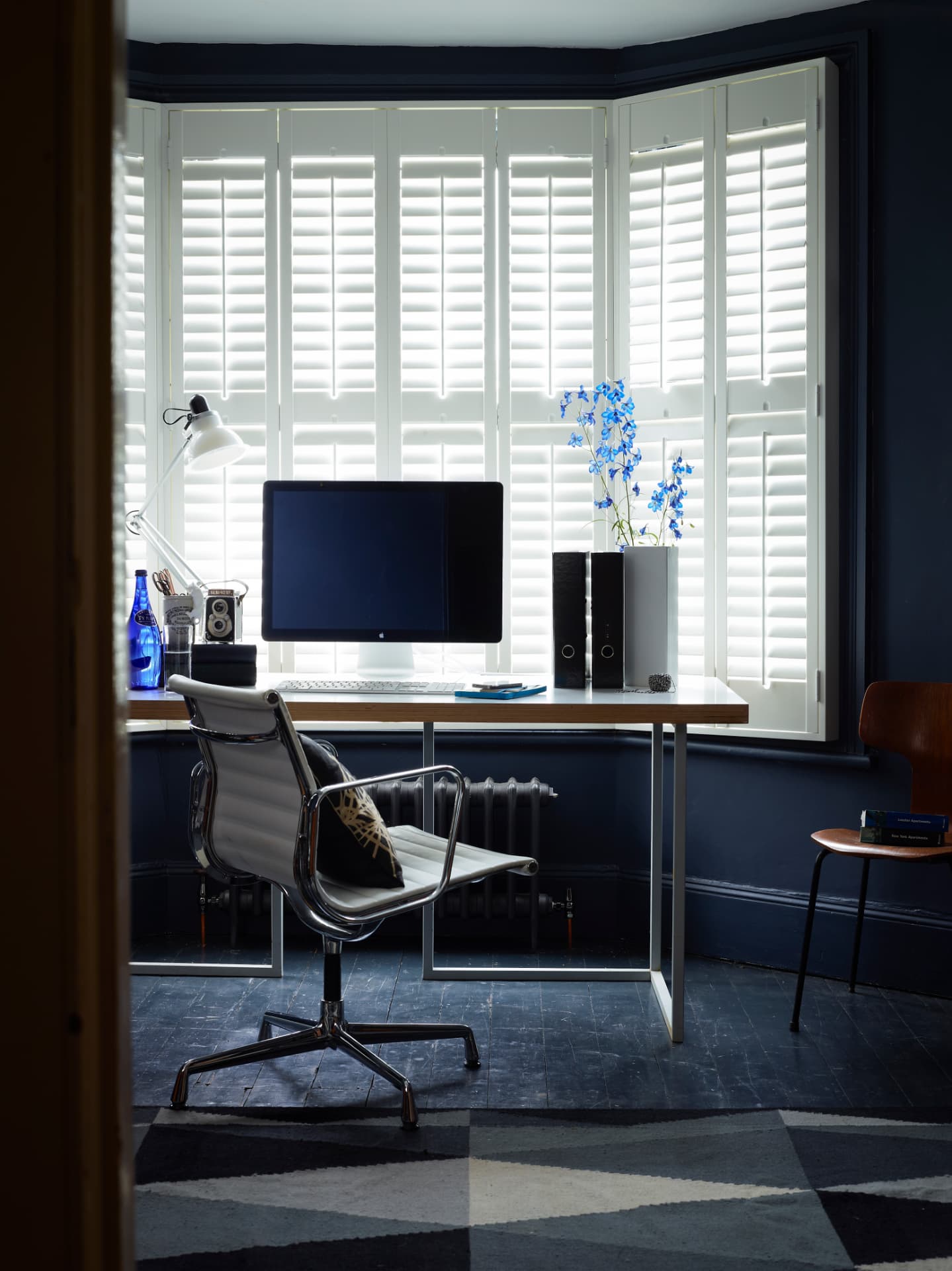 Shutters in a dark blue bay window home office