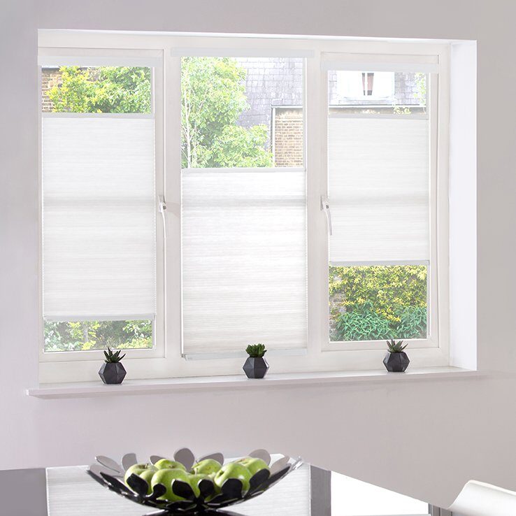 White cellular blinds on a three-pane window with a bottom-up fit