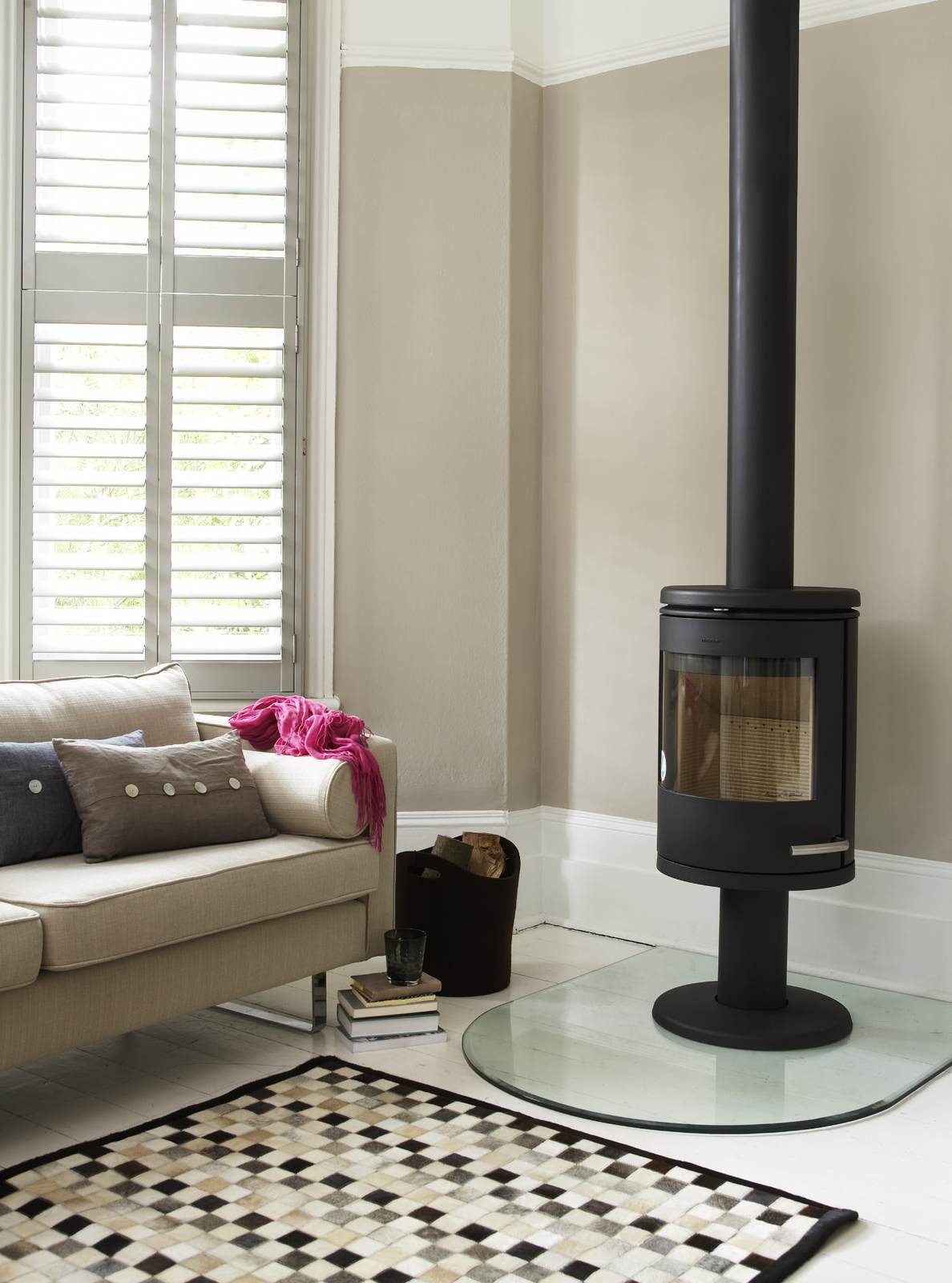 Tier-on-tier shutters beside a wood burning stove in a neutral lounge