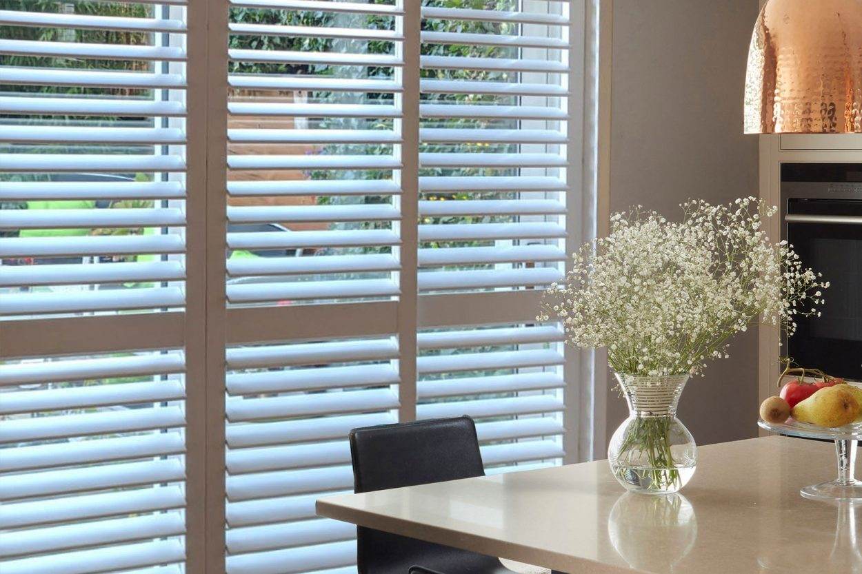 Close-up of white shutter louvres beside a dining table
