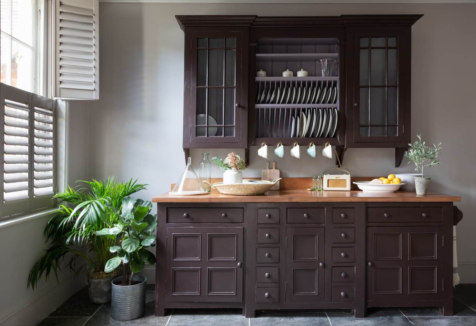Off-white tier-on-tier shutters beside a painted kitchen dresser
