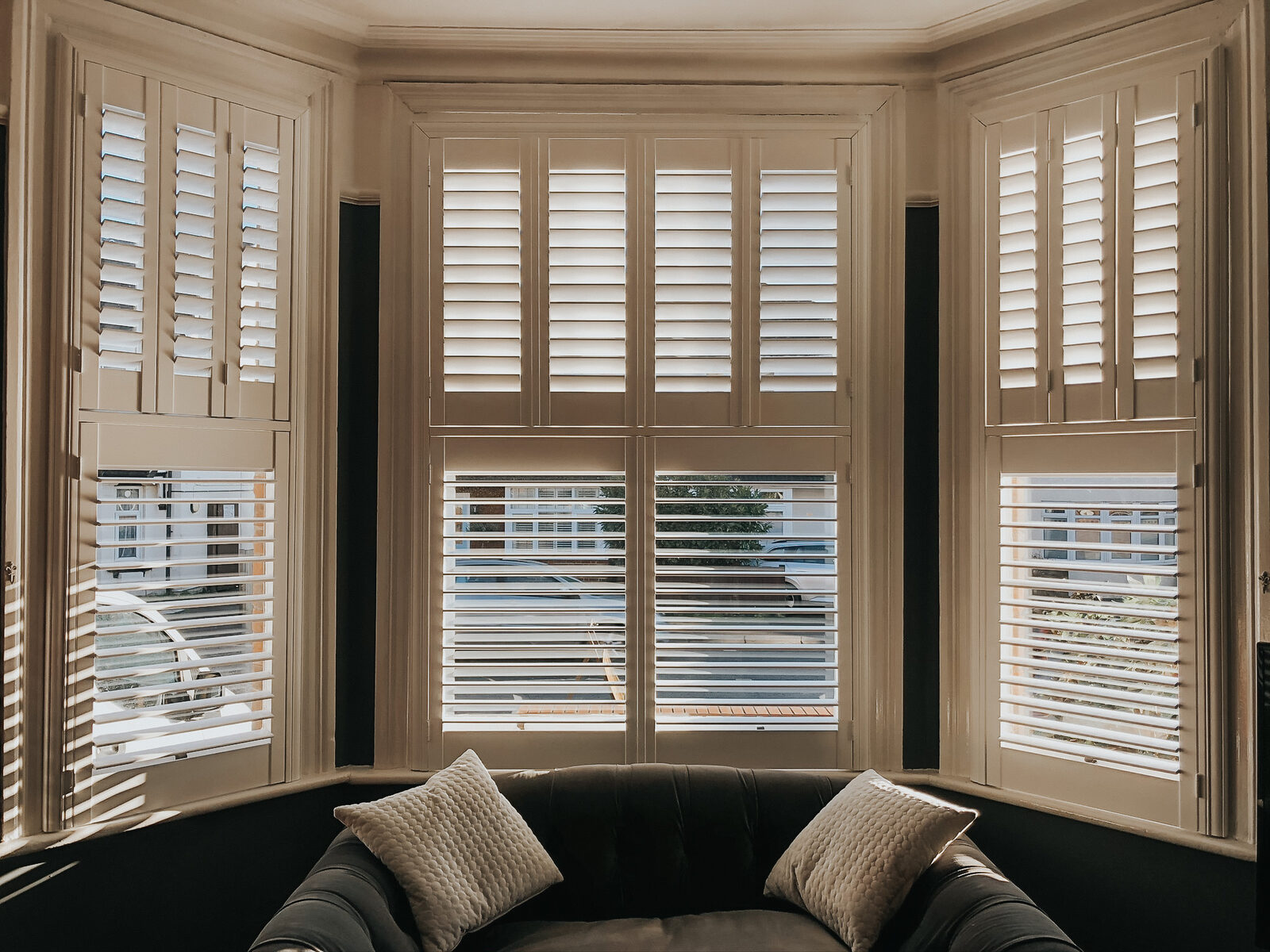 Taupe shutters around a bay window seat with cushions