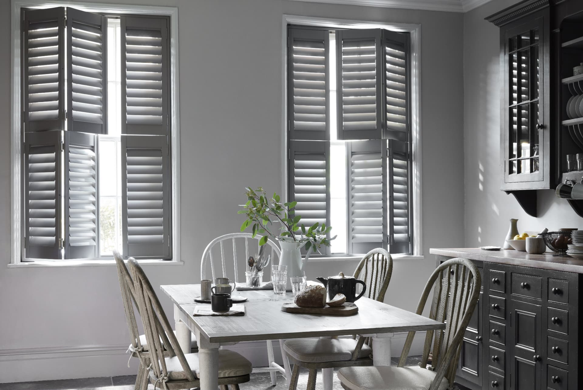 Grey tier-on-tier shutters with 76mm louvres in a kitchen dining room